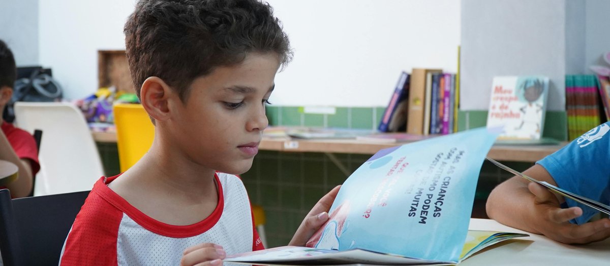 Pessoa lendo livro entre pilhas de livros, representando a inteligência linguística