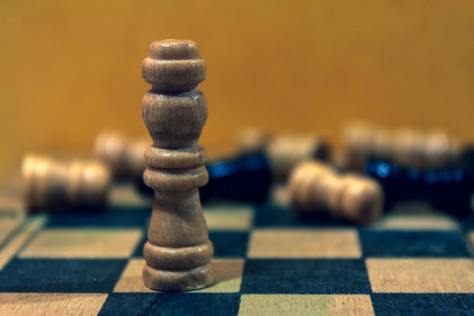 Peça de rei em pé num tabuleiro com peças derrubadas ao redor